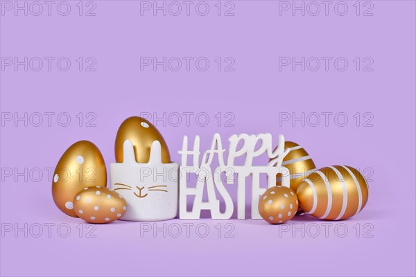 Golden easter eggs and text Happy easter on violet background