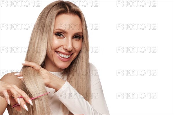 Beautiful blond girl with a perfectly hair, and classic make-up with scissors in hand. Beauty face and hair. Picture taken in the studio