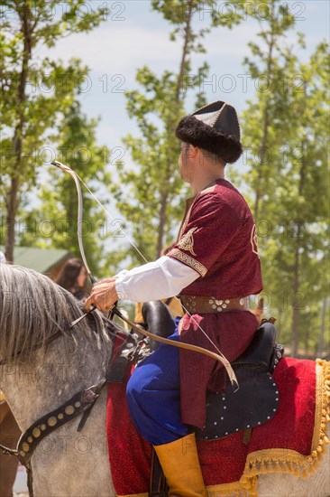 Archer with bow in traditional clothes shooting an arrow