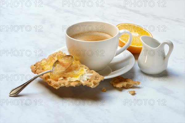 Orange marmalade in small bowls and on crispbread and cup of coffee