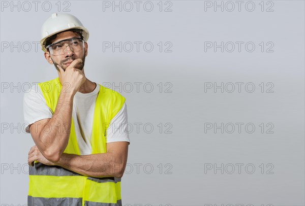 Pensive builder man with hand on chin, Portrait of young builder thinking with hand on chin isolated, A pensive engineer on white background. Concept of a meditative engineer solated