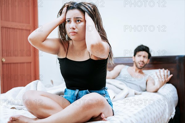 Young couple arguing sitting on the bed. Concept of couple problems in bed. Upset woman with husband sitting on bed, Wife arguing with her husband in bed