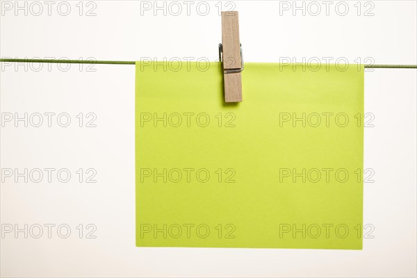 Sticky note hung with a clothespin on a clothesline with copy space and white background