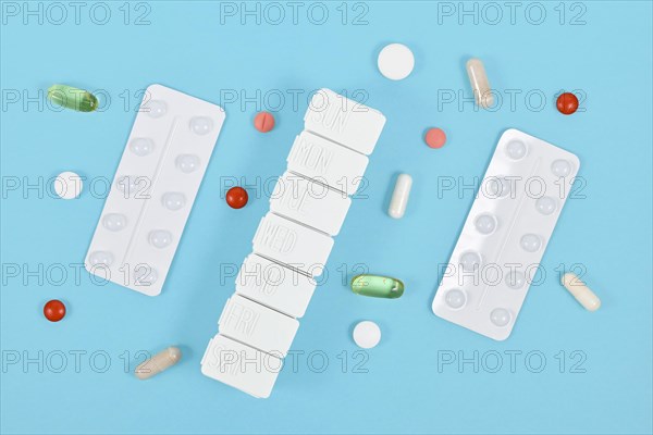 Pills, capsules, blister packs and pill box on blue background