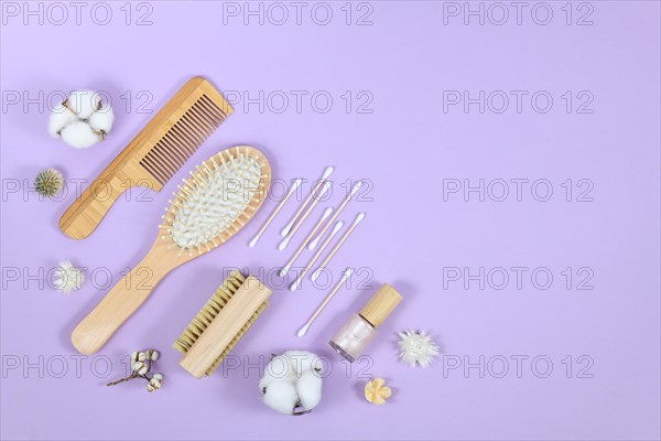 Eco friendly wooden beauty and hygiene products like comb and soap in corner of purple background with copy space