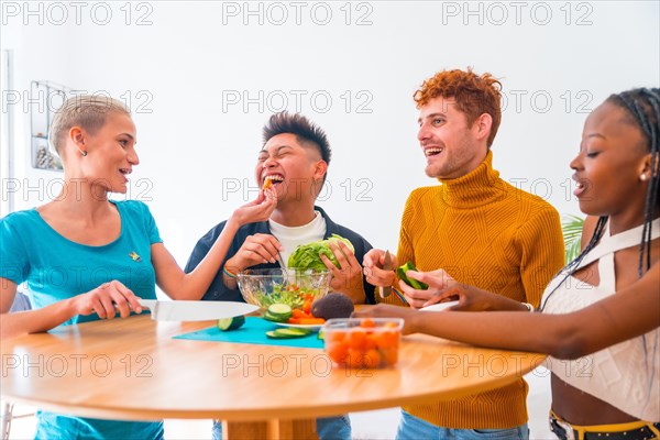 Group of friends preparing vegetarian food. Preparing the salad and having fun in the kitchen