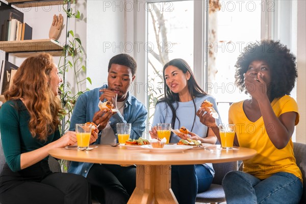 Friends at a breakfast with orange juice and muffins at home, having fun in domestic life