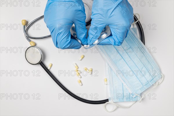 Stethoscope, medical accessories, hands pushing pills out of blister, on white background