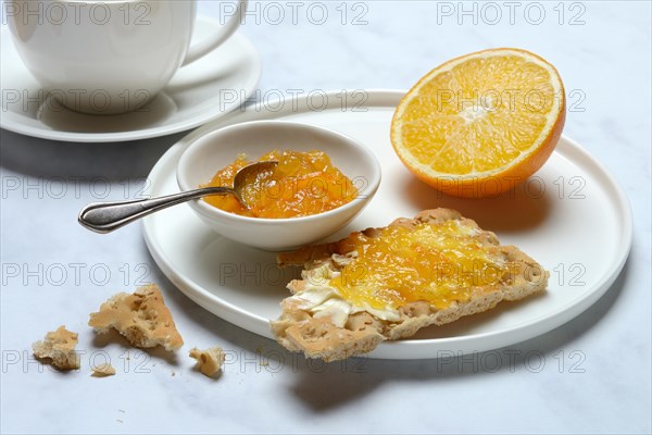 Orange marmalade in small bowls and on crispbread