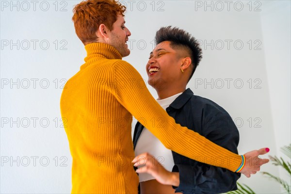 Beautiful gay couple having fun and dancing indoors at home, lgbt concept