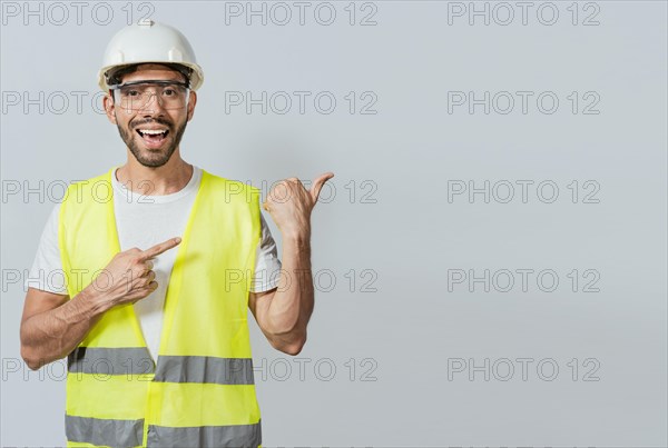Construction engineer with vest pointing at an advertisement. Engineer man pointing to side. Builder engineer pointing finger to the right isolated, Portrait of engineer man pointing aside