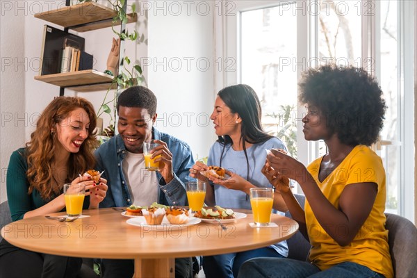 Friends at a breakfast with orange juice and muffins at home, having fun in the morning