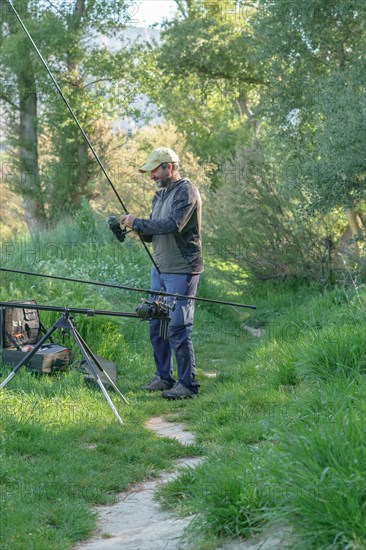 Man with beard and cap preparing his fishing gear on the river bank