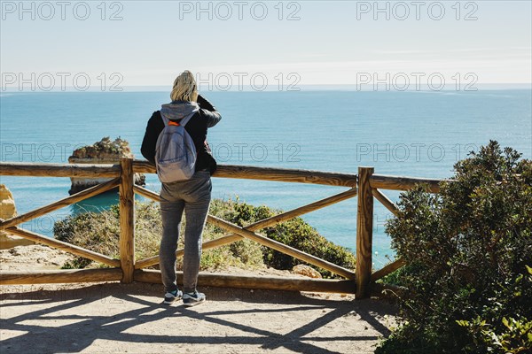 A woman enjoying the Atlantic Ocean from the top of cliffs at Marinha Beach in Algarve, Portugal, Europe