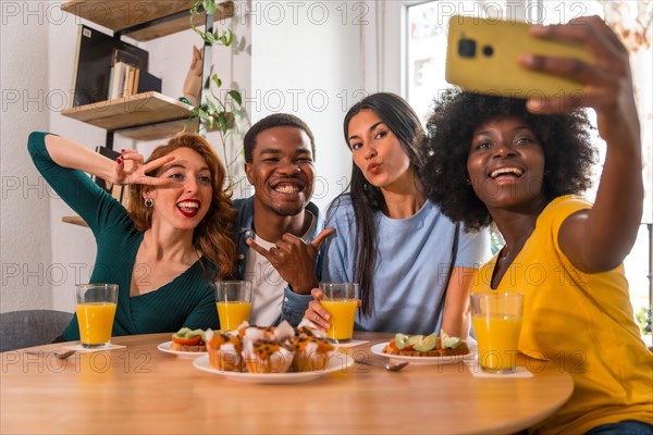 Multiethnic friends at a breakfast with orange juice and muffins at home, taking a selfie