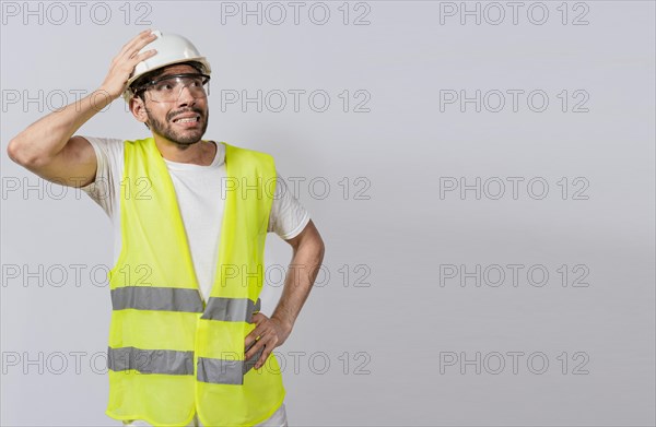 Worried builder engineer holding his head. Worried engineer man looking up. Troubled young engineer holding his head looking up. Engineer problems concept