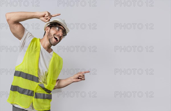 Builder engineer pointing finger to the right isolated, Construction engineer with vest pointing at an advertisement. Engineer man pointing to side. Smiling engineer man pointing aside