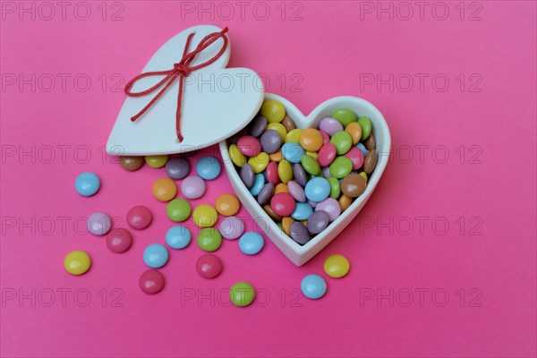 Chocolate lentils in heart-shaped container, Smartie