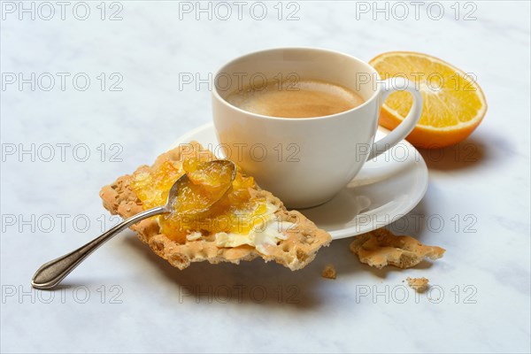 Orange marmalade in small bowls and on crispbread and cup of coffee