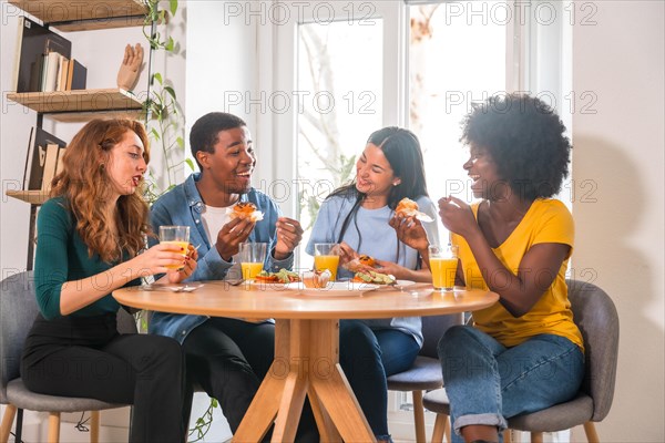 Friends at a breakfast with orange juice and muffins at home, having fun in domestic life