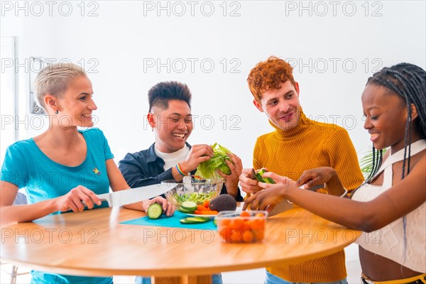 Group of friends preparing a salad. They prepare food and have fun in the kitchen