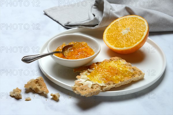 Orange marmalade in small bowls and on crispbread