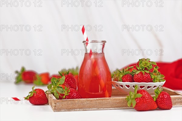 Jar with red strawberry fruit lemonade surrounded by berries