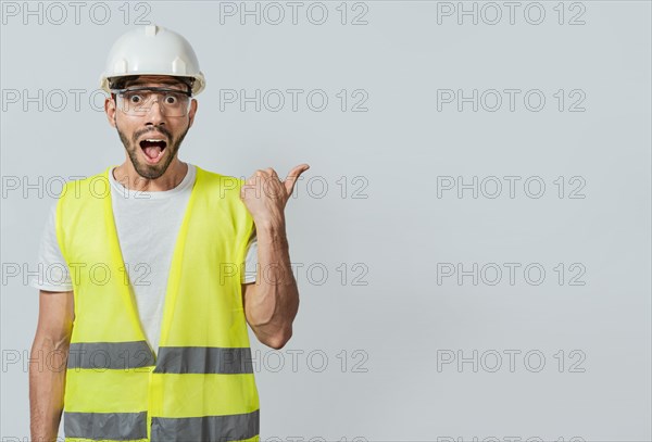 Surprised face construction worker pointing at an advertisement. Engineer man pointing to side. Surprised face engineer pointing finger to the right, Surprised engineer pointing to the side