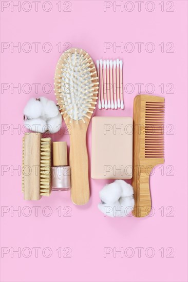Eco friendly wooden beauty and hygiene products like comb and soap arranged on pink background