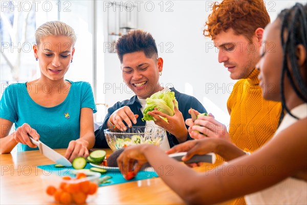 Group of friends preparing vegetarian food. Preparing the salad and having fun in the kitchen