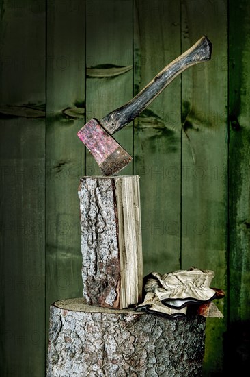 Axe on chopping block with log in front of green wooden wall, studio shot, Germany, Europe