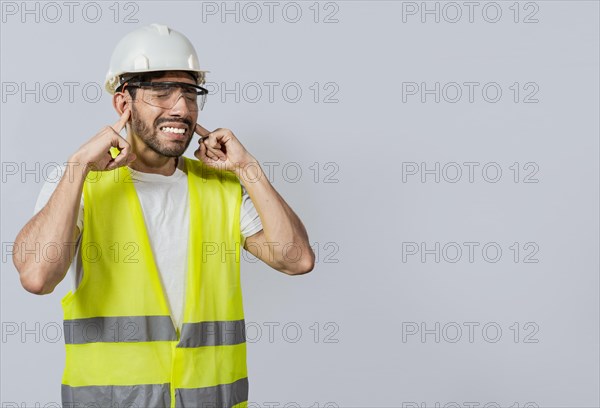 Engineer with ear pain isolated, Young engineer covering his ears isolated, Builder man with ear pain, Concept of engineer covering his ears with pain expression