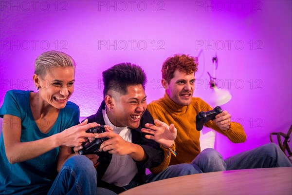 Group of young friends playing video games together on the sofa at home, purple led, having fun pushing