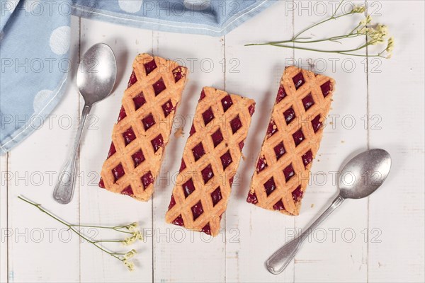 Rectangular slices of pie called Linzer Torte, a traditional Austrian shortcake pastry topped with fruit preserves and sliced nuts with lattice design