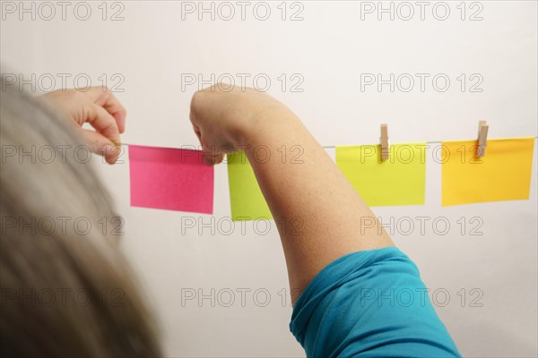 Woman hanging postit on a clothesline with wooden tongs