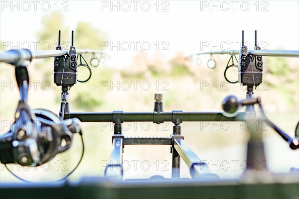 Close-up of a rod holder with alarms and two rods with their reels in fishing action