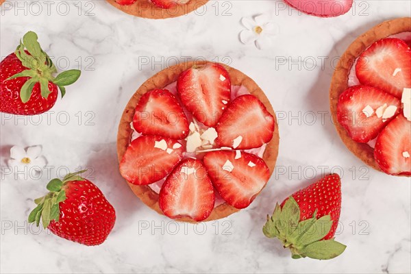 Single strawberry tartlet pastry topped with fruits and white chocolate sprinkles