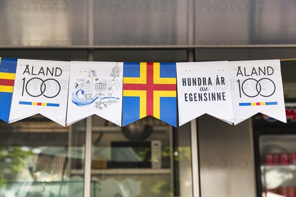 Various pennants for the anniversary, inscription 100 years of stubbornness, autonomy, flag Aland, Mariehamn, Aland Islands, Finland, Europe