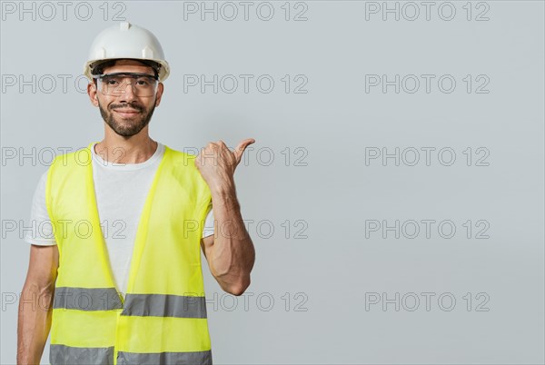 Portrait of engineer man pointing aside. Construction worker with vest pointing at an advertisement. Engineer man pointing to side. Builder engineer pointing finger to the right isolated