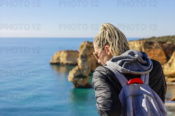 A woman enjoying the Atlantic Ocean from the top of cliffs at Marinha Beach in Algarve, Portugal, Europe