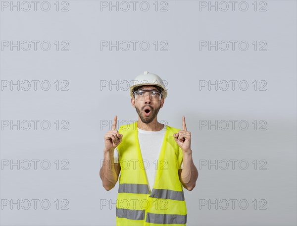 Surprised young architect pointing up, Amazed engineer pointing at an advertisement. Concept of an engineer with astonished face pointing at blank space, Amazed engineer man pointing up