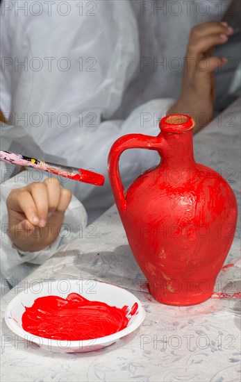 Young children decorating their handmade clay pottery