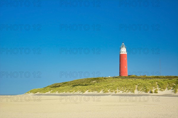 Lighthouse at northern beach of island Texel in Netherlands on summer day with blue sky