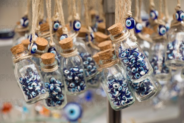 Little transparent glass bottle filled with blue evil eye beads