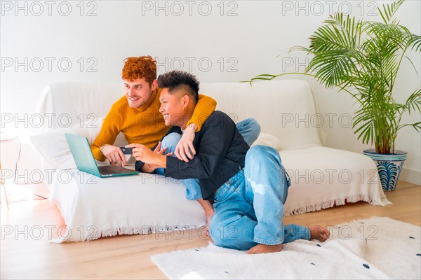 Beautiful gay couple being romantic on the sofa hugging, lgbt concept, doing online shopping