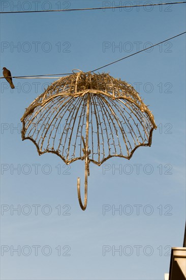 Beautiful umbrella of golden color hanging in the street for decorative purposes