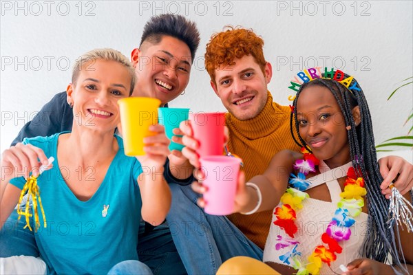 Lgtb couples of gay boys and girls lesbian in a portrait on a sofa at a house party, birthday party, toasting with colored glasses