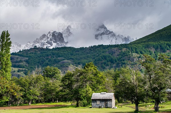 Shingle-roofed wooden house in front of snow-capped mountains, Villa Cerro Castillo, Cerro Castillo National Park, Aysen, Patagonia, Chile, South America