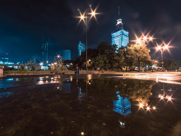 Night cityscape with reflections in the puddle