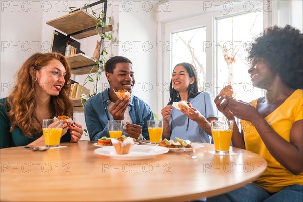 Friends at a breakfast with orange juice and muffins at home, healthy lifestyle having fun in the morning